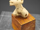 sculpture représentant un chien assis sur un bloc de bois posé sur une table