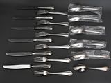 a lot of forks and knives on a black table