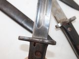 someone is holding a knife in their hand with two other knives in the background