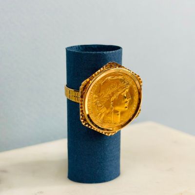 une pièce d'or posée sur un cylindre bleu, sur une table