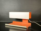 une lampe de bureau orange et blanche posée sur une table noire