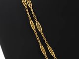 a gold plated necklace with a long chain that is attached to a mannequin