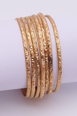 un gros plan sur une pile de bracelets en or posés sur une serviette