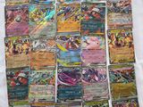 a pile of pokemon cards sitting on top of a white sheet
