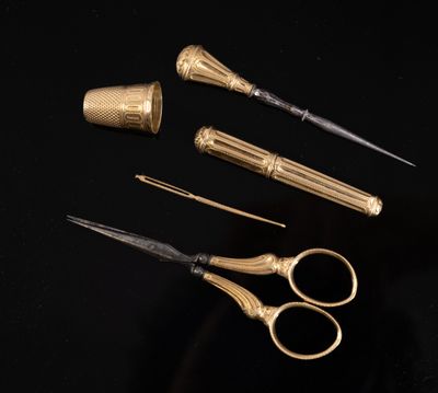 three pairs of gold scissors and a pair of silver scissors on a black surface