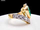an image of a gold ring with a green stone surrounded by white diamonds