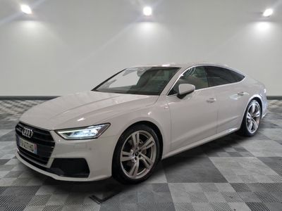 une Audi blanche garée dans une grande pièce au sol à carreaux