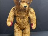 an old teddy bear sitting on top of a black surface