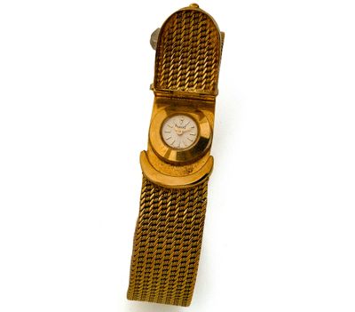 une montre en or entourée d'une chaîne sur une surface blanche