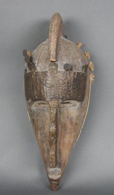 une image d'un masque en bois accroché au mur