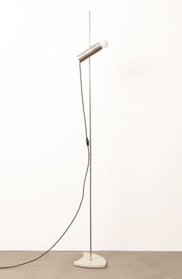 un lampadaire blanc posé sur un sol en béton, à côté d'un mur blanc