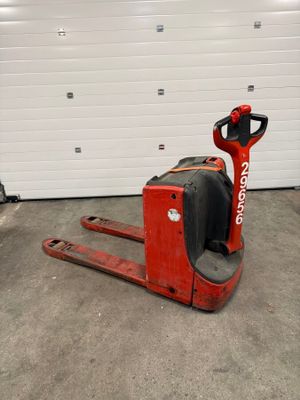 un chariot élévateur rouge dans un garage, avec une porte de garage en arrière-plan