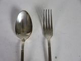 two spoons and a fork on a white table