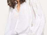 a woman wearing a white blouse and jeans posing for a picture