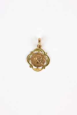 a small gold pendant with a coin in the center