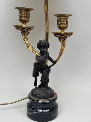 a statue of a boy holding a candelab with three candles on it