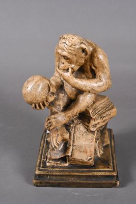 statue of a man with a book and a ball sitting on a book