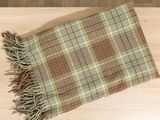 a plaid blanket with fringes on a wooden table