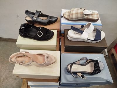 Plusieurs paires de chaussures pour femmes sont posées sur des cartons, sur une table.
