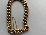 gros plan d'un bracelet en chaîne en or sur une surface blanche