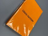 un sac Louis Vuitton orange posé sur une surface grise, à côté d'une paire de chaussures