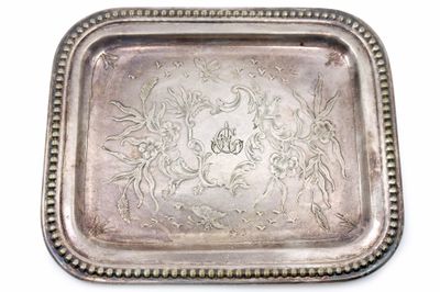 un plateau en argent orné d'un motif sur fond blanc