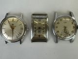 three watches are sitting on a white surface next to each other