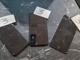 Trois téléphones portables sont posés sur une table, avec un mot accroché à chacun d'eux.