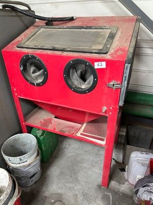 a red stove sitting in a garage next to a trash can