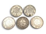six pièces de monnaie britanniques différentes sont disposées en ligne sur une surface blanche