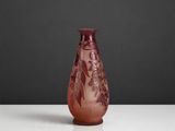 un vase en verre violet posé sur une table blanche, sur fond noir