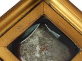 a gold framed mirror with a red dot in it