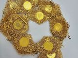 a close up of a gold coin wreath on a white surface