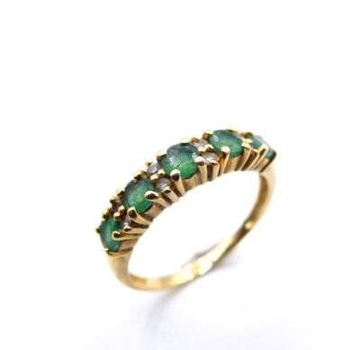 a close up of a gold ring with green stones