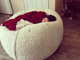 a woman laying on a bean bag chair in a living room
