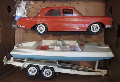 deux petites voitures et un bateau dans une boîte