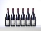 six bottles of red wine are lined up on a table