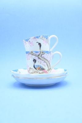 une tasse et une soucoupe posées sur une assiette, sur un fond bleu