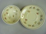 two cups and saucers with floral designs on them sitting on a table