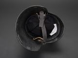 an old black helmet with a leather strap on a black background