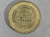 a close up of a coin on a white surface with a building in the background