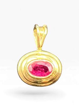 a close up of a gold pendant with a pink stone