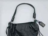 a black purse with a zipper on the side and a tag attached to it