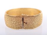 a close up of a gold bracelet on a white surface