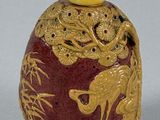 a red and gold vase with a bird on it