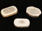 three pieces of white and gold jewelry sitting on a black surface
