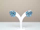 une paire de boucles d'oreilles en cristal bleu posées sur un support blanc, sur une table