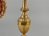 a gold candle holder with a red flower on top of it