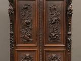 une vieille armoire en bois avec des gravures et des sculptures sur les portes