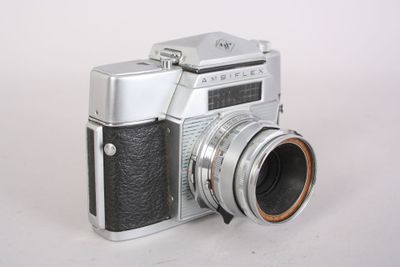 a silver and black camera on a white surface